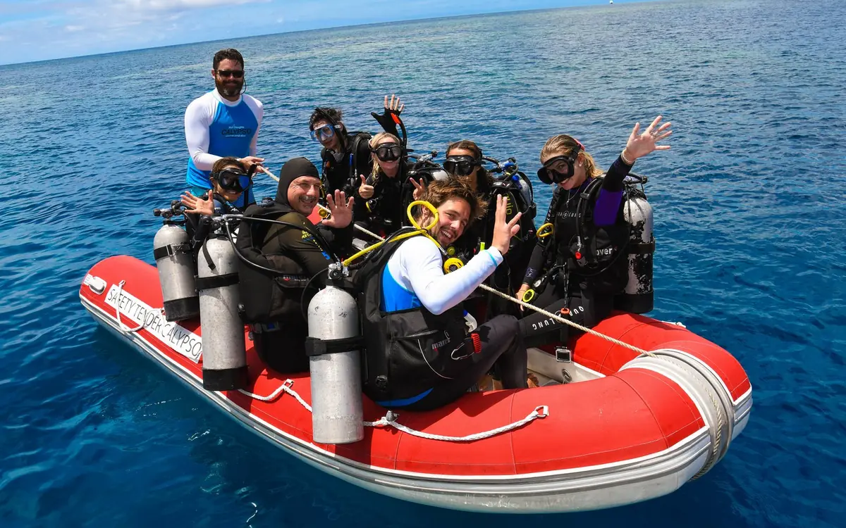 Divers in the water beside a boat on the Great Barrier Reef