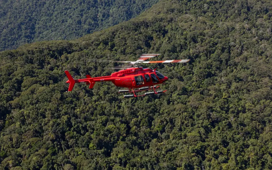 A helicopter over rainforest and a waterfall near Cairns