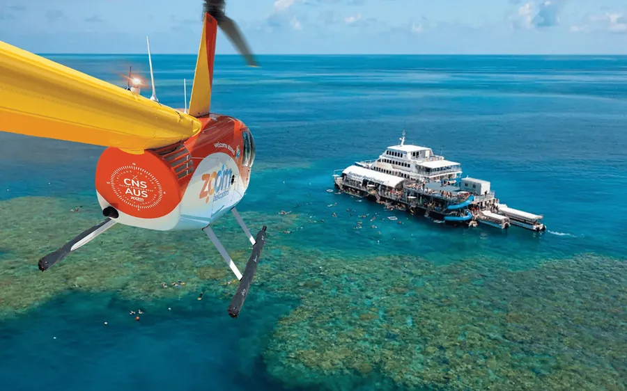 A helicopter beside the reef pontoon with a boat moored alongside